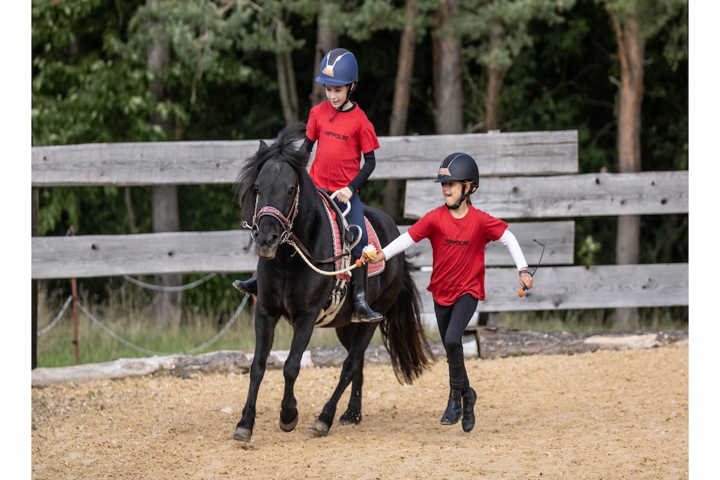 Zwei Kinder im HIPPOLINI Unterricht. Ein Kind führt das Pony, das andere reitet. Darstellung des reformpädagogischen Methodenkerns zur Trennung von Balance und Einwirkung.